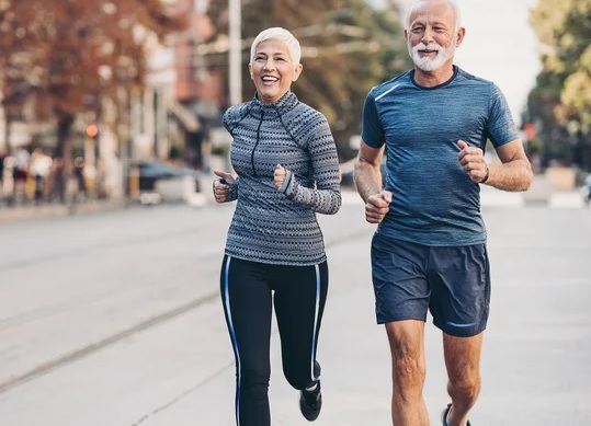 Muskarac i zena u zrelim godinama obuceni u sportsku odecu trce gradskom ulicom