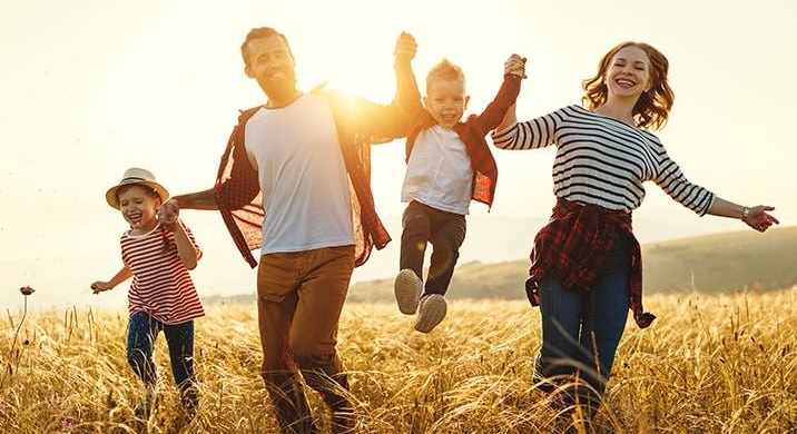 Nasmejani i razigrani mama tata isin i kcerka trce poljem suve trave