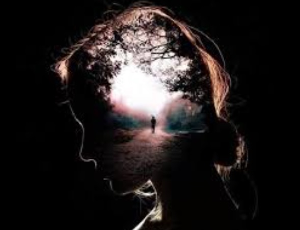 Na crnoj pozadini slikaprofila žene u cijoj glavi je slika malog coveka koji hoda sumskim putem