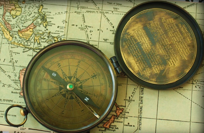 Otvoren starinski kompas leži na delu karte sveta