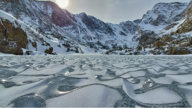 Zaleđeni talasi okruzeni sneznim planinama