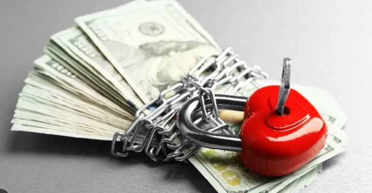 Srce katanac sa kljucem zakacen na lanac obmotan oko sveznja novcanica